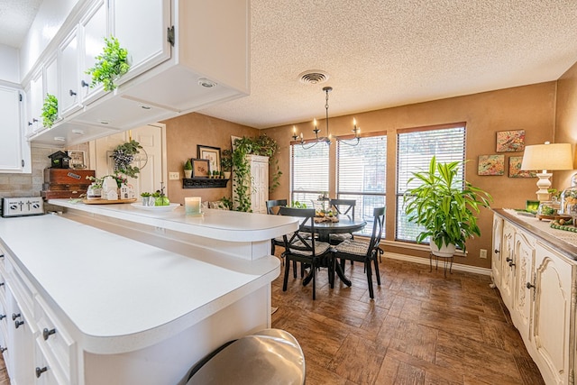 3615 W Wadley Ave, Midland, TX 79707 - kitchen with a textured ceiling, white cabinetry, light countertops, and a chandelier