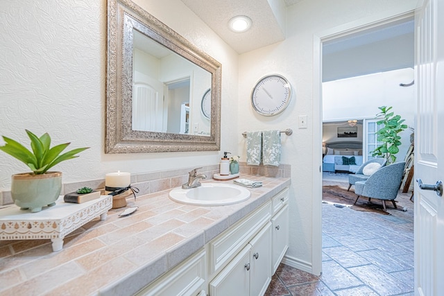 3615 W Wadley Ave, Midland, TX 79707 - bathroom with vanity, a textured wall, and stone tile floors