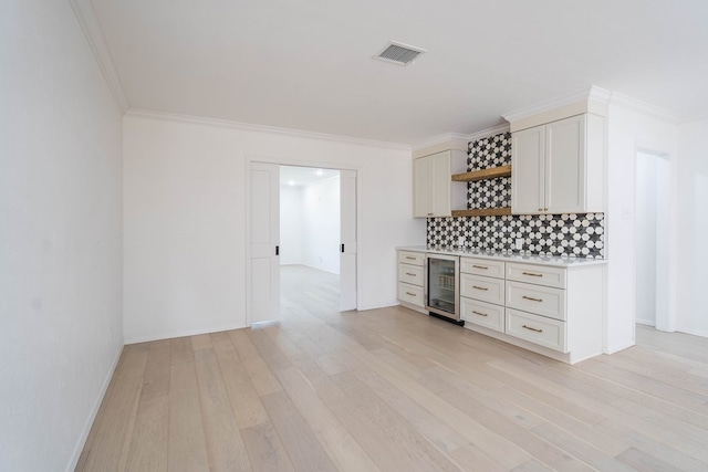 kitchen with light hardwood / wood-style floors, beverage cooler, ornamental molding, and white cabinetry