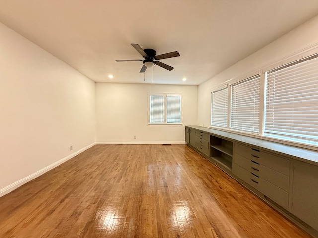 interior space with built in desk, ceiling fan, and light wood-type flooring