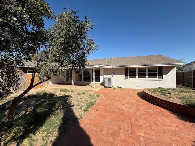 rear view of property featuring a patio, brick siding, central AC, and fence