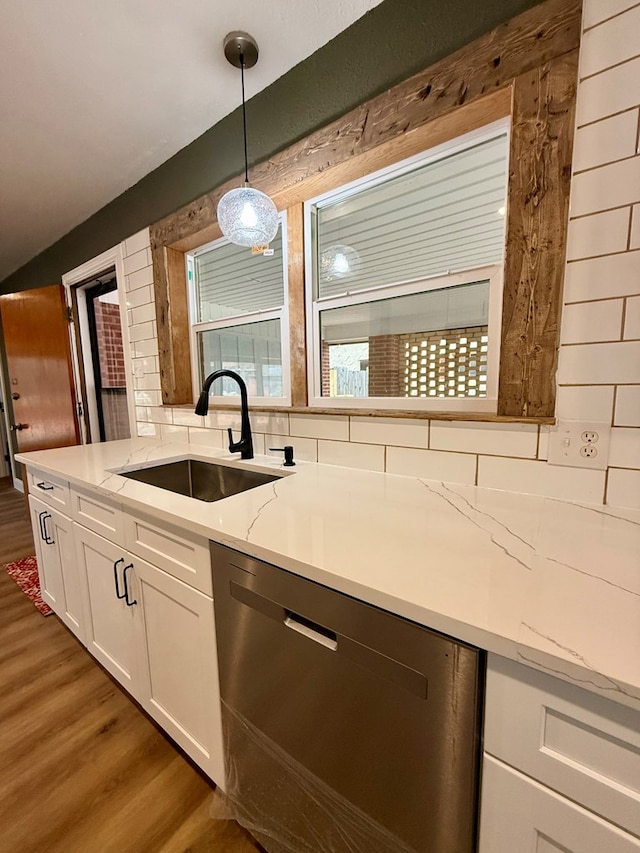 kitchen featuring dishwasher, white cabinetry, sink, hanging light fixtures, and light stone counters