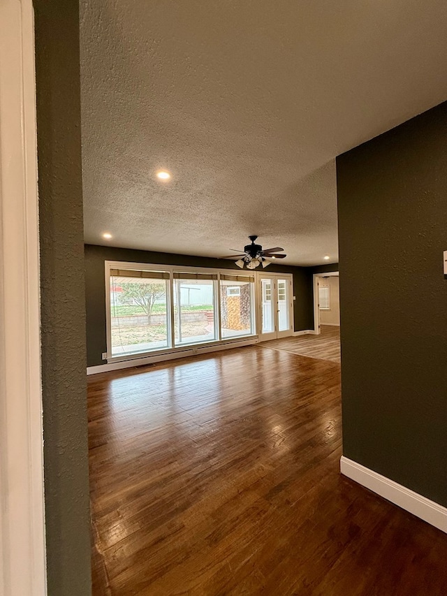 unfurnished living room featuring hardwood / wood-style flooring, ceiling fan, and a textured ceiling