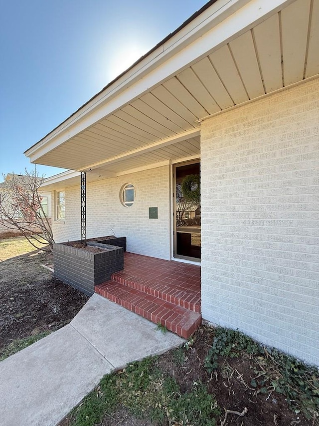 view of exterior entry featuring brick siding