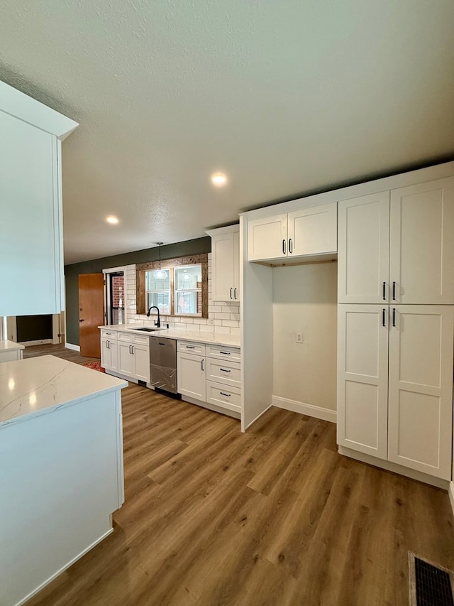 kitchen featuring dishwasher, white cabinetry, wood-type flooring, decorative backsplash, and decorative light fixtures