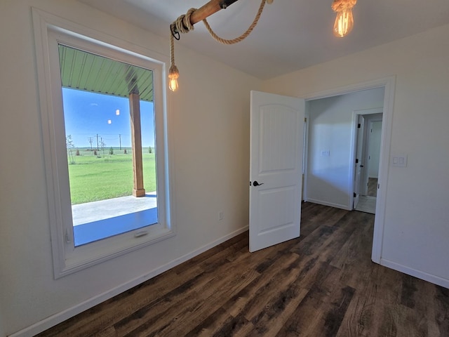 spare room featuring dark wood-type flooring and plenty of natural light