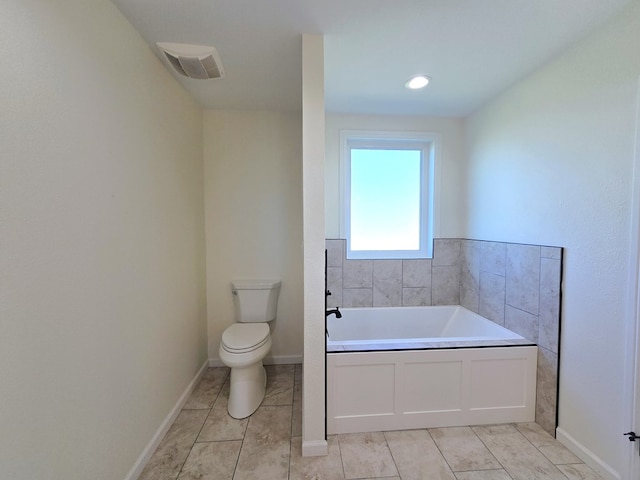 bathroom featuring tile patterned floors, a tub to relax in, and toilet