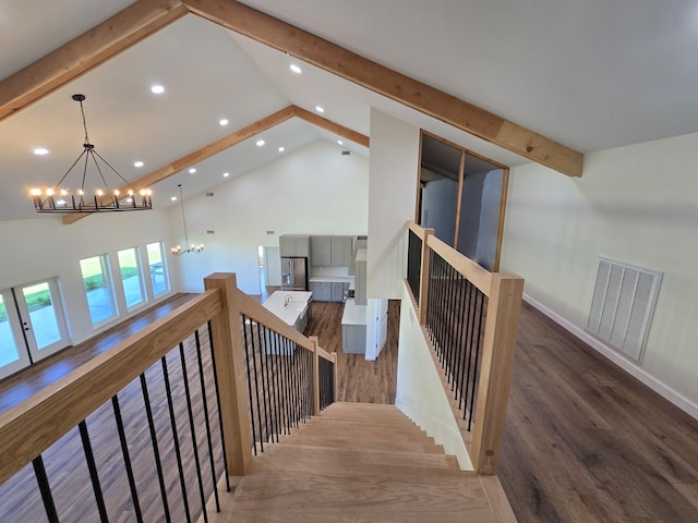 staircase featuring wood-type flooring, a chandelier, and high vaulted ceiling