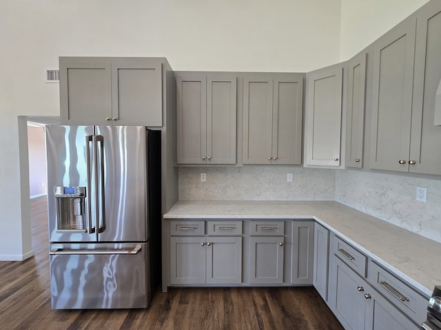 kitchen featuring light stone countertops, dark wood-type flooring, backsplash, stainless steel fridge, and gray cabinets