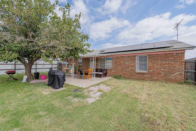 rear view of property featuring solar panels, a patio, an outdoor living space, and a yard