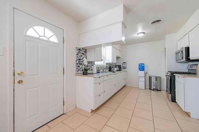 kitchen with white cabinetry, sink, stainless steel appliances, tasteful backsplash, and light tile patterned floors