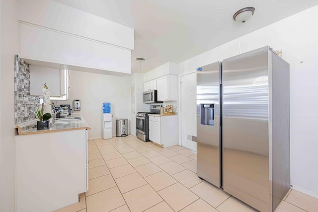 kitchen with pendant lighting, white cabinets, sink, light tile patterned floors, and appliances with stainless steel finishes