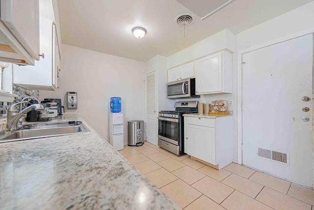 kitchen with stainless steel appliances, white cabinetry, and sink