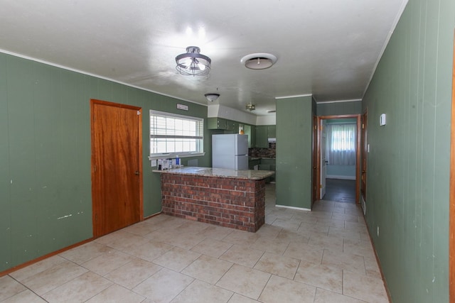 207 W Robinson Rd, Big Spring, TX 79720 - kitchen with freestanding refrigerator, a peninsula, crown molding, and light tile patterned floors