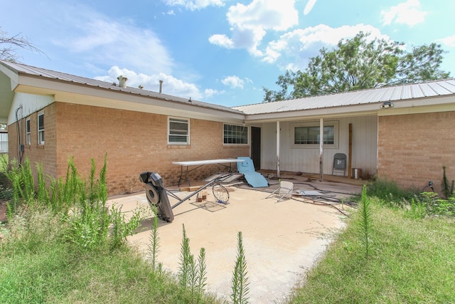 207 W Robinson Rd, Big Spring, TX 79720 - rear view of house featuring brick siding, a patio, and a metal roof