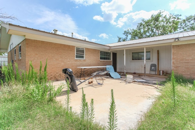 207 W Robinson Rd, Big Spring, TX 79720 - rear view of property with a patio area, brick siding, and a metal roof