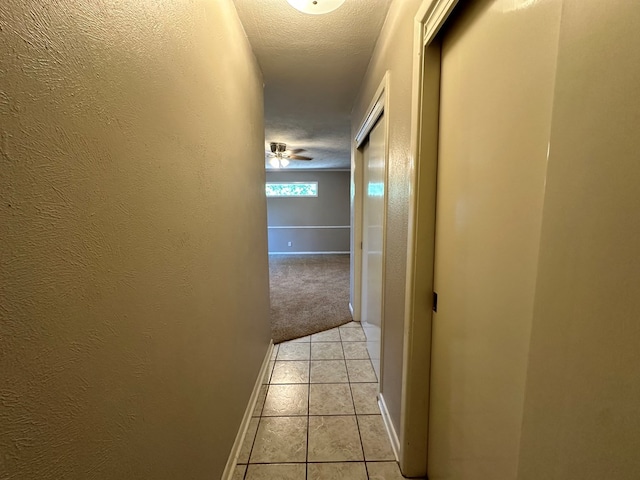 hallway with light tile patterned floors and a textured ceiling