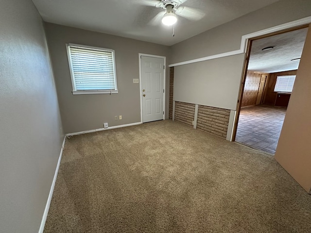 carpeted empty room with ceiling fan, plenty of natural light, and a textured ceiling