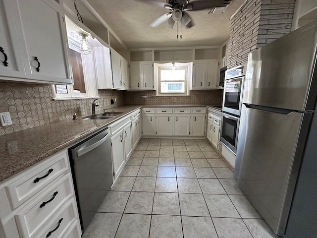 kitchen with white cabinetry, sink, decorative backsplash, light tile patterned floors, and appliances with stainless steel finishes