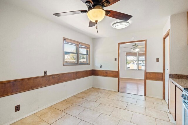 tiled spare room featuring ceiling fan and a healthy amount of sunlight