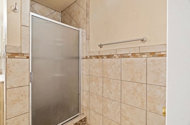 bathroom with an enclosed shower and tile walls