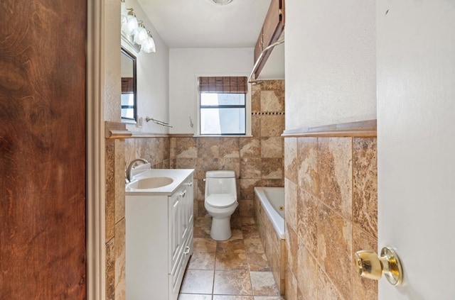 bathroom featuring vanity, a bathtub, toilet, and tile walls