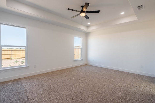 carpeted spare room featuring a tray ceiling, recessed lighting, visible vents, a ceiling fan, and baseboards