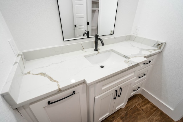 bathroom featuring a textured wall, wood tiled floor, baseboards, and vanity