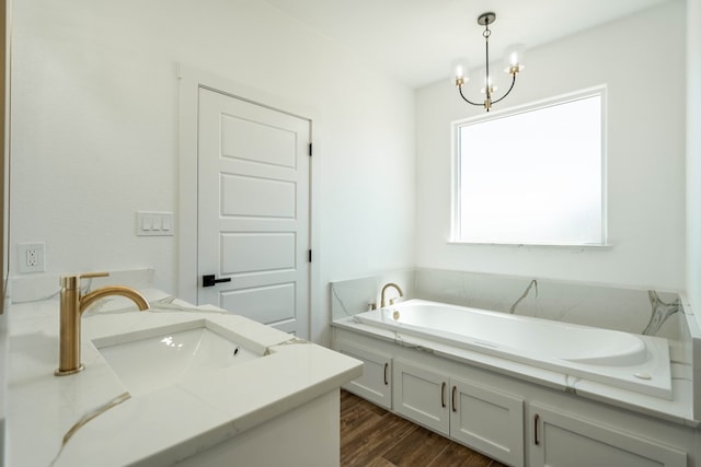 full bathroom with a chandelier, wood finished floors, vanity, and a bath