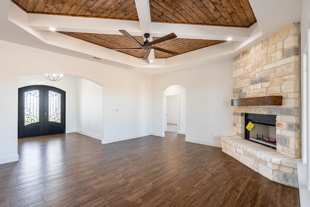 unfurnished living room featuring arched walkways, wooden ceiling, dark wood-type flooring, baseboards, and french doors