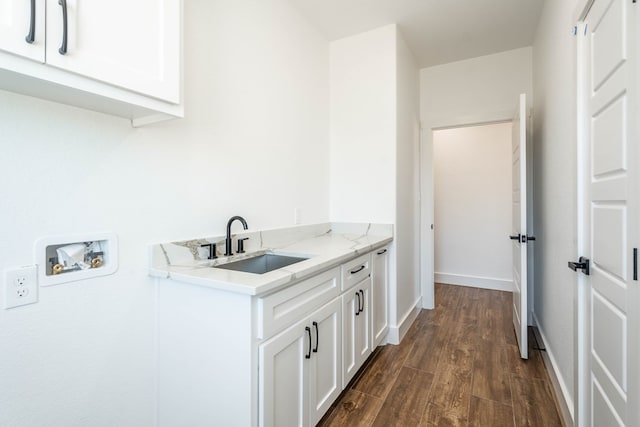 interior space featuring dark wood-style floors, washer hookup, cabinet space, a sink, and baseboards