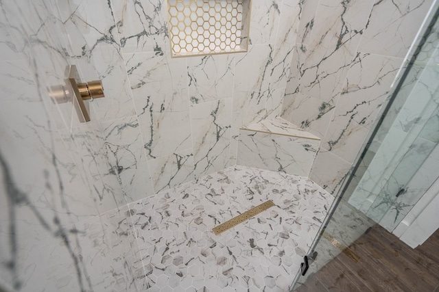 interior details featuring wood finished floors and a tile shower