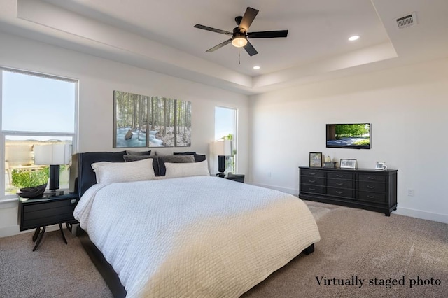 bedroom featuring a tray ceiling, multiple windows, and visible vents