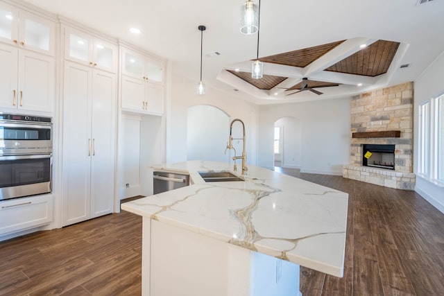 kitchen featuring white cabinets, a sink, glass insert cabinets, and pendant lighting