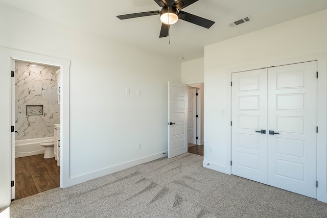 unfurnished bedroom with ensuite bathroom, light carpet, a closet, and ceiling fan