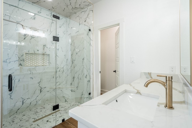 full bathroom with vanity, a marble finish shower, and wood finished floors