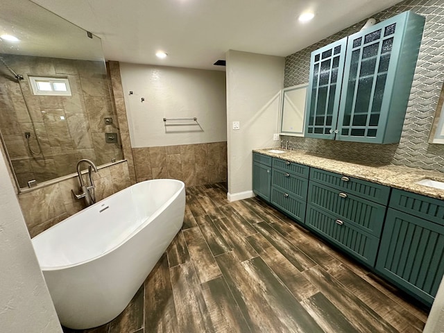 bathroom with hardwood / wood-style floors, vanity, separate shower and tub, and tile walls