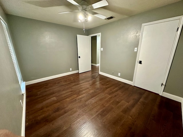 unfurnished bedroom with ceiling fan, dark wood-type flooring, and a textured ceiling