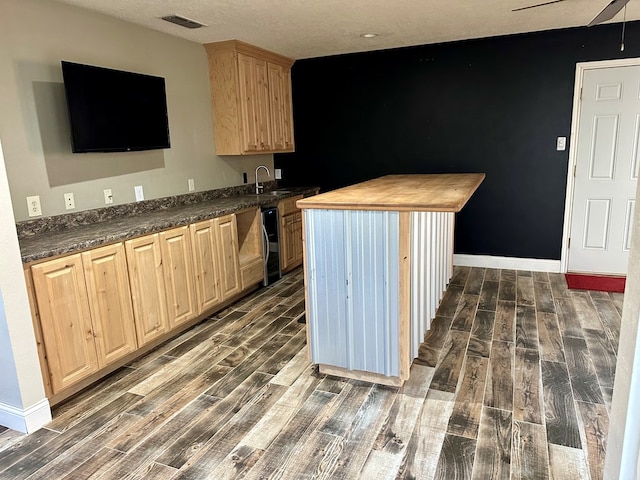 kitchen featuring light brown cabinets, dark wood-type flooring, and a textured ceiling