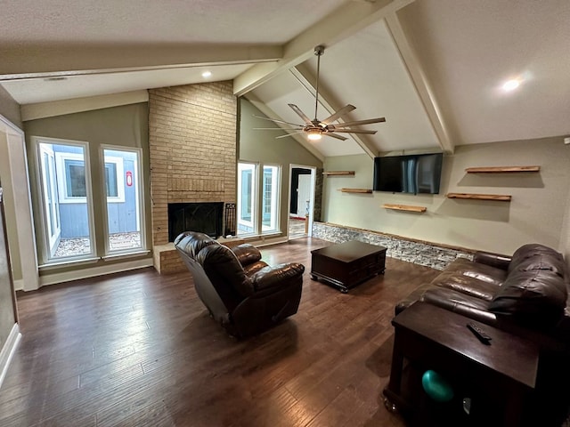 living room with lofted ceiling with beams, dark hardwood / wood-style floors, ceiling fan, a textured ceiling, and a fireplace