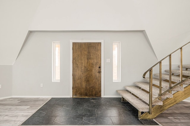 entryway featuring lofted ceiling, stairs, and baseboards