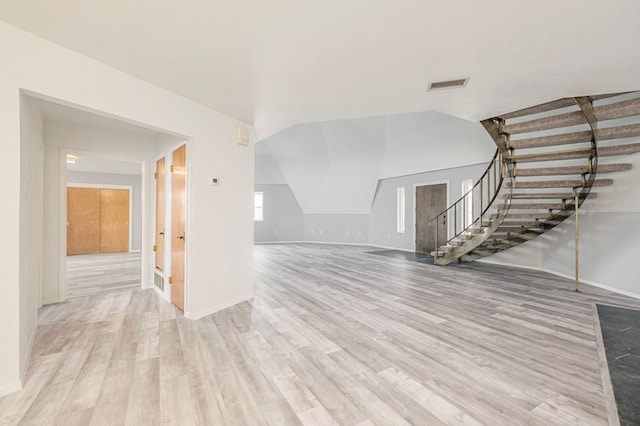 unfurnished living room with stairs, lofted ceiling, visible vents, and light wood-style floors