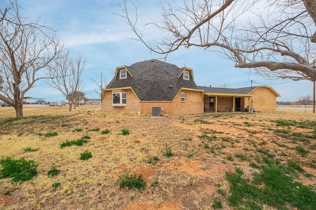 back of house featuring brick siding and central air condition unit