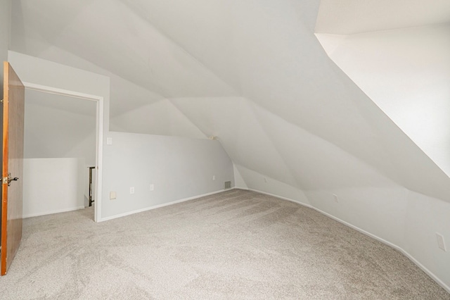 additional living space featuring carpet flooring, vaulted ceiling, and baseboards