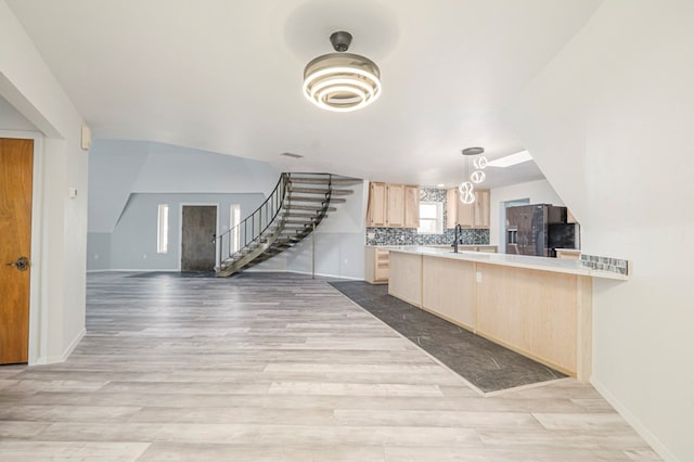 kitchen featuring tasteful backsplash, wood finished floors, light countertops, light brown cabinetry, and black fridge