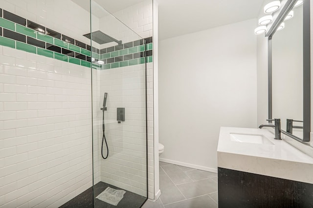 full bath featuring toilet, a tile shower, vanity, baseboards, and tile patterned floors