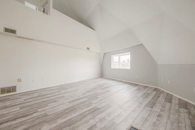 bonus room with light wood-style floors, visible vents, and high vaulted ceiling