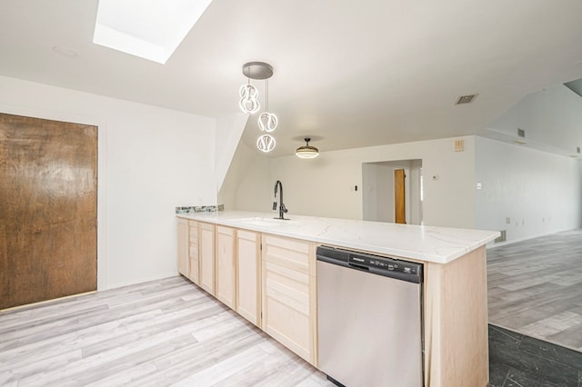 kitchen featuring a peninsula, a sink, open floor plan, stainless steel dishwasher, and light brown cabinetry