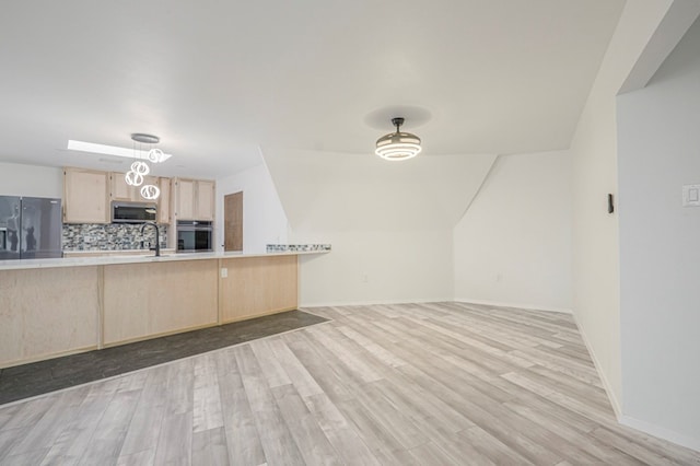 kitchen with light wood finished floors, stainless steel appliances, light brown cabinetry, and light countertops