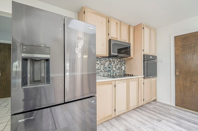 kitchen featuring light wood finished floors, tasteful backsplash, light countertops, light brown cabinetry, and black appliances